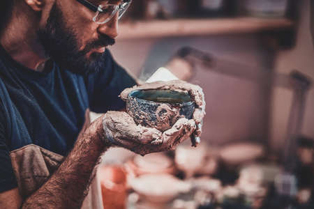 Closeup photoshoot of working process with clay by diligent man.