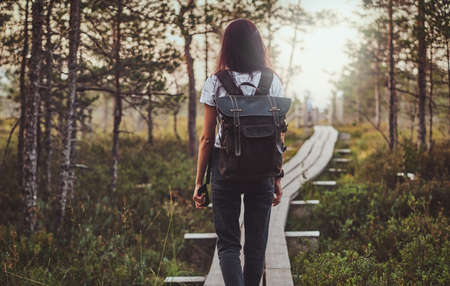 Skinny young woman is hiking by the wooden path in the middle of lush pine forest.の写真素材