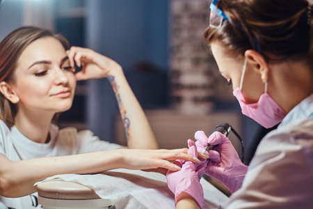 Process of manicure at beuaty salon with two attractive happy womens.の写真素材