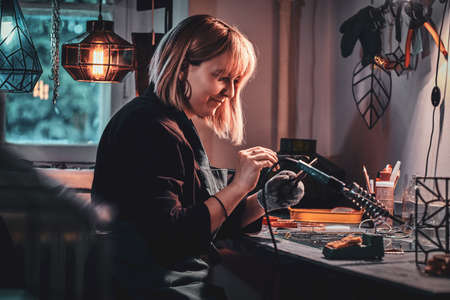 Happy smiling designer is working at her own glass studio on her new project.