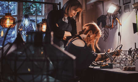 Expirienced master and her new assistant are working together doing new lamp.