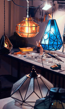Masters workspace, table and beautiful colourful glass lamps at cozy workshop.の写真素材
