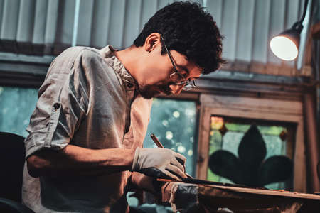 Expirienced diligent restorer is working on antique stained glass restoration at his own workshop.の写真素材