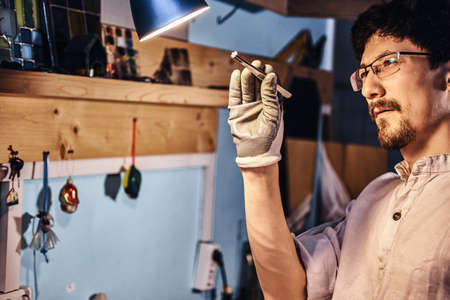 Dilligent focused master is looking for right  peace of glass for his project.の写真素材