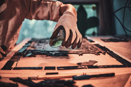 Craftsman is applying another piece of stained glass to the broken antique window.