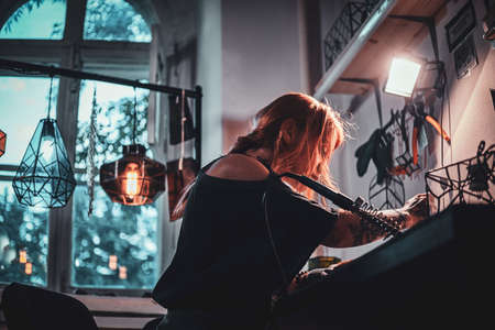 Talanted young woman is working on her own project at glass workshop.