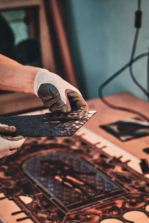 Restorer is choosing right peace of stained glass for his beautiful vintage project.の写真素材