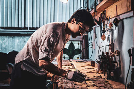 Pensive craftman is restoring ancient broken stained glass at his own workplace.の写真素材