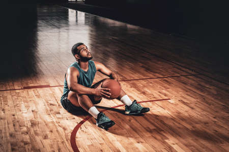 Portrait of Black basketball playersits on a floor in a basketball hall.の写真素材
