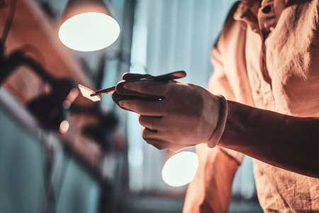 Craftsman at his restouration workshop with plies and peace of stained glass in his hands.の写真素材