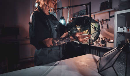 Young smiling designer is happy about her new lamp, wich she is holding in hands.の写真素材