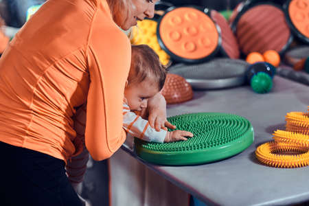 Little pretty baby is curious about special treatment toy at masseur cabinet.