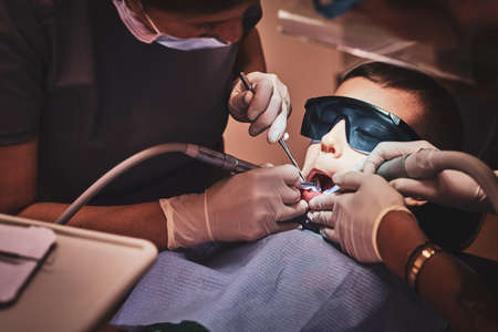 Brave small child gets a dental treatment by expirienced doctor at dental clinic.の写真素材