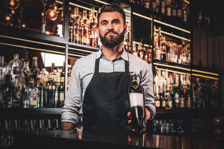 Happy smiling barman is offering special rare wine for customers at his cozy bar.の写真素材