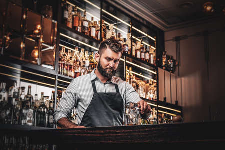 Happy smiling barman is prepairing drinks for customers at posh bar.の写真素材