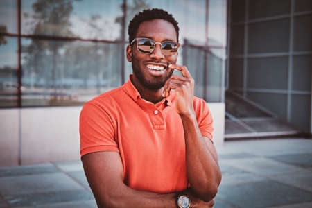 Portrait of happy smiling afro student in sunglasses over glass building.の写真素材
