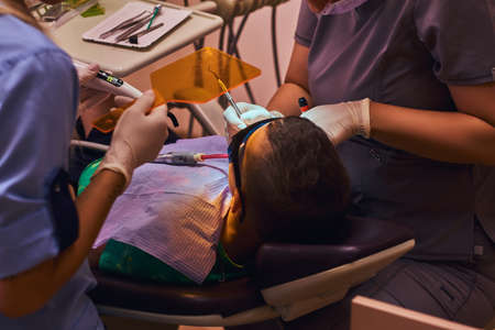 Little brave boy has a dental operation by dentist and her assistant at hospital.の写真素材