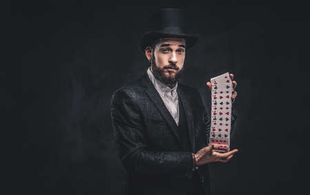 Magician showing trick with playing cards on a dark background.の写真素材