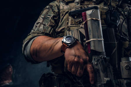 Closeup photo shoot of mans hand holding machine gun. Man is wearing military uniform and wach.の写真素材