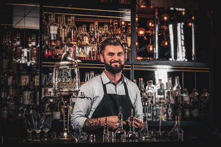 Happy cheerful barman is relaxing at his own bar while waiting for customers.の写真素材