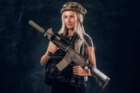 Beautiful fragile blond girl with machine gun in full army uniform and helmet.の写真素材