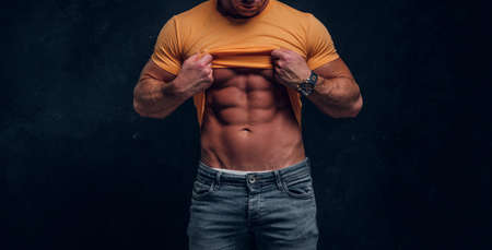 Sexual muscular bodybuilder is showing his well done sixpack at dark studio.の写真素材