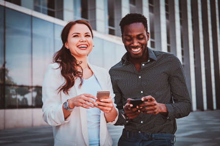 Two joyful busines partners are meeting up near glass building at city centre.の写真素材