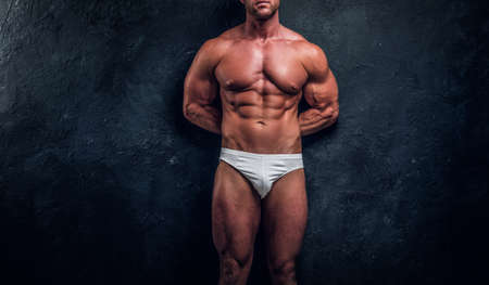 Sexual muscular bodybuilder is showing his beautiful body for photoset at dark studio.の写真素材