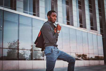 Portrait of pensive modern afro man with sunglasses and blazer in his hands.の写真素材