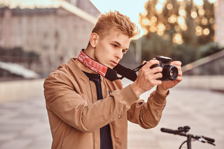 Young pensive photographer is making photos with his digital photo camera.