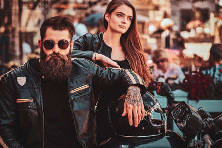Beautiful couple with brutal biker and his sexy gilfriend are chilling near cefeteria with motorbike.の写真素材