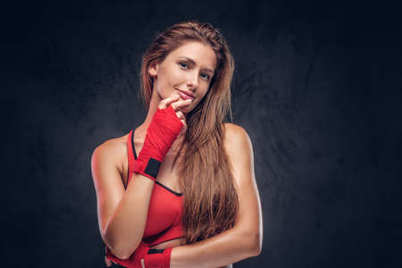 Attractive brunette in red gloves and sport bra is posing for photographer at studio.の写真素材