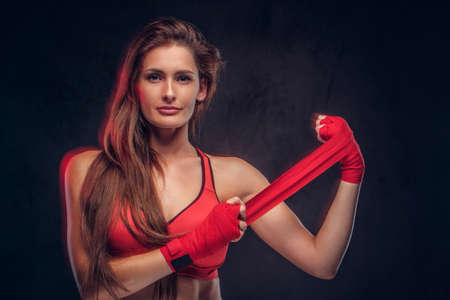 Beautiful cheerful woman in red bra is wearing her gloves before boxing.の写真素材