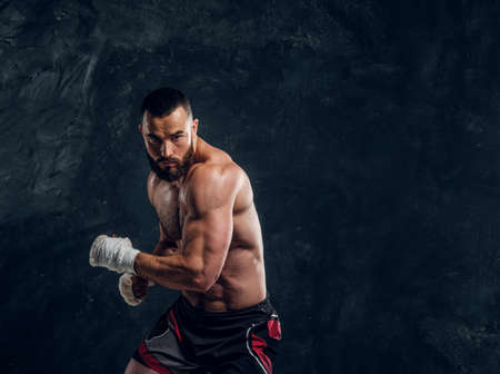 Manly bearded man with beautiful muscular torso is posing for photographer on the dark background.の写真素材