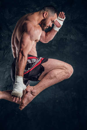 Focused physically fit man is jumping, making illusion of flight before punch an dark studio.の写真素材
