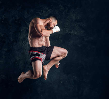 Focused physically fit man is jumping, making illusion of flight before punch an dark studio.の写真素材