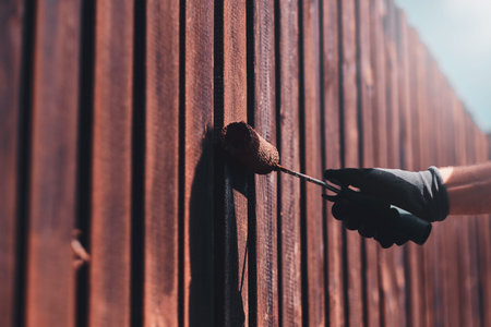 Process of fence renovation at bright sunny day by man in protective gloves.