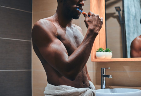 Black african man is brushing his teeth at bathroom at mourning.