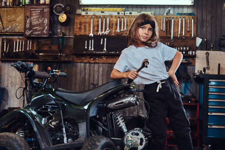 Serious beautiful girl want to be an auto technician when she grows up, she is trying to fix broken ATV.の写真素材