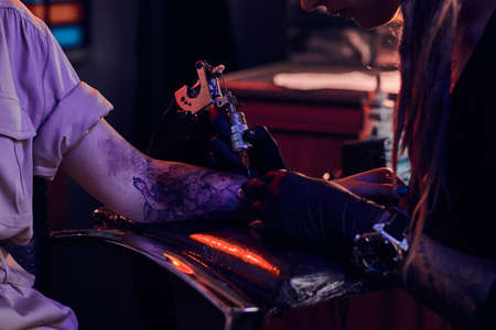 Closeup photo shoot of tattoo making, artist is working with tattoo machine on customers hand.の写真素材
