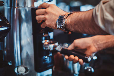 Diligent barista is prepairing fresh latte for customers for coffee break at caffeteria.の写真素材