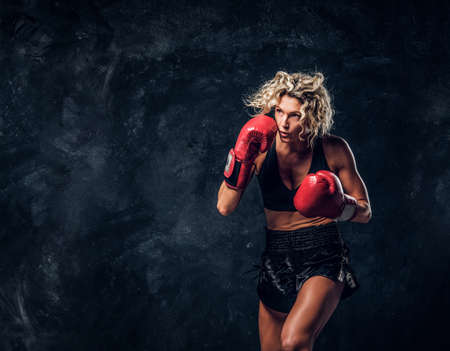 Sportive muscular woman is demonstrating her boxing exercises, wearing gloves.の写真素材