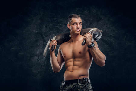 Muscular attractive hot man is holding weight bag while posing for photographer.の写真素材