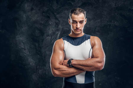 Portrait of muscular handsome man in wetsuit crossed his hands over dark background.の写真素材