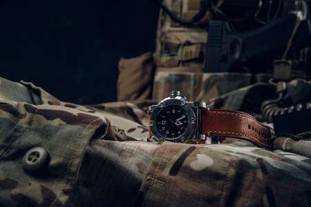 Still life with nice watch and military uniform with typical camo pattern and gun.の写真素材