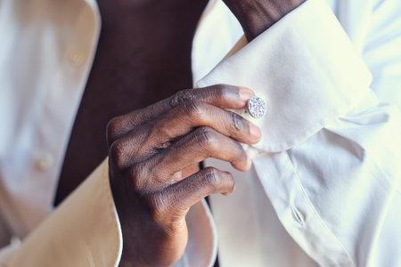 Closeup photo shoot of african american man in white open shirt with diamond cufflink in hand.の写真素材