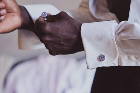 Closeup photo shoot of african american man in white shirt with diamond cufflink in hand.の写真素材