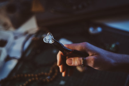 Creative woman is holding pliers and crystal clear quartz in it.