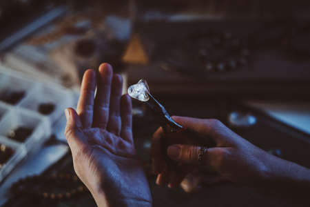 Creative woman is holding pliers and crystal clear quartz in it.の写真素材