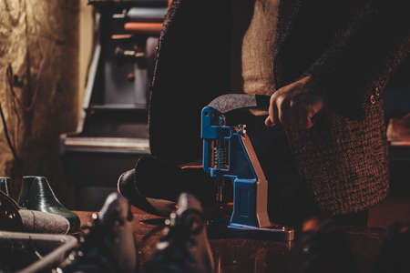 Experienced shoes master is making holes for laces in shoes using special tool.の写真素材